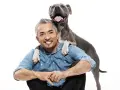 Cesar Millan z uśmiechniętym psem, który kładzie mu łapy na ramionach.