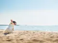 Francuski buldog cieszy się wakacjami z psem nad morzem, siedząc na piaszczystej plaży i patrząc na błękitną wodę.